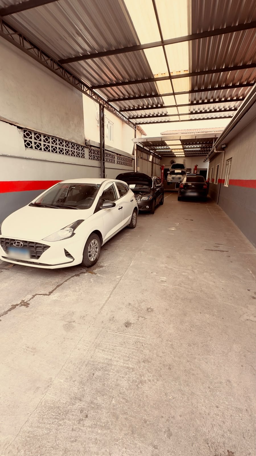 Pátio coberto da oficina Revisa Automotiva com carros aguardando atendimento